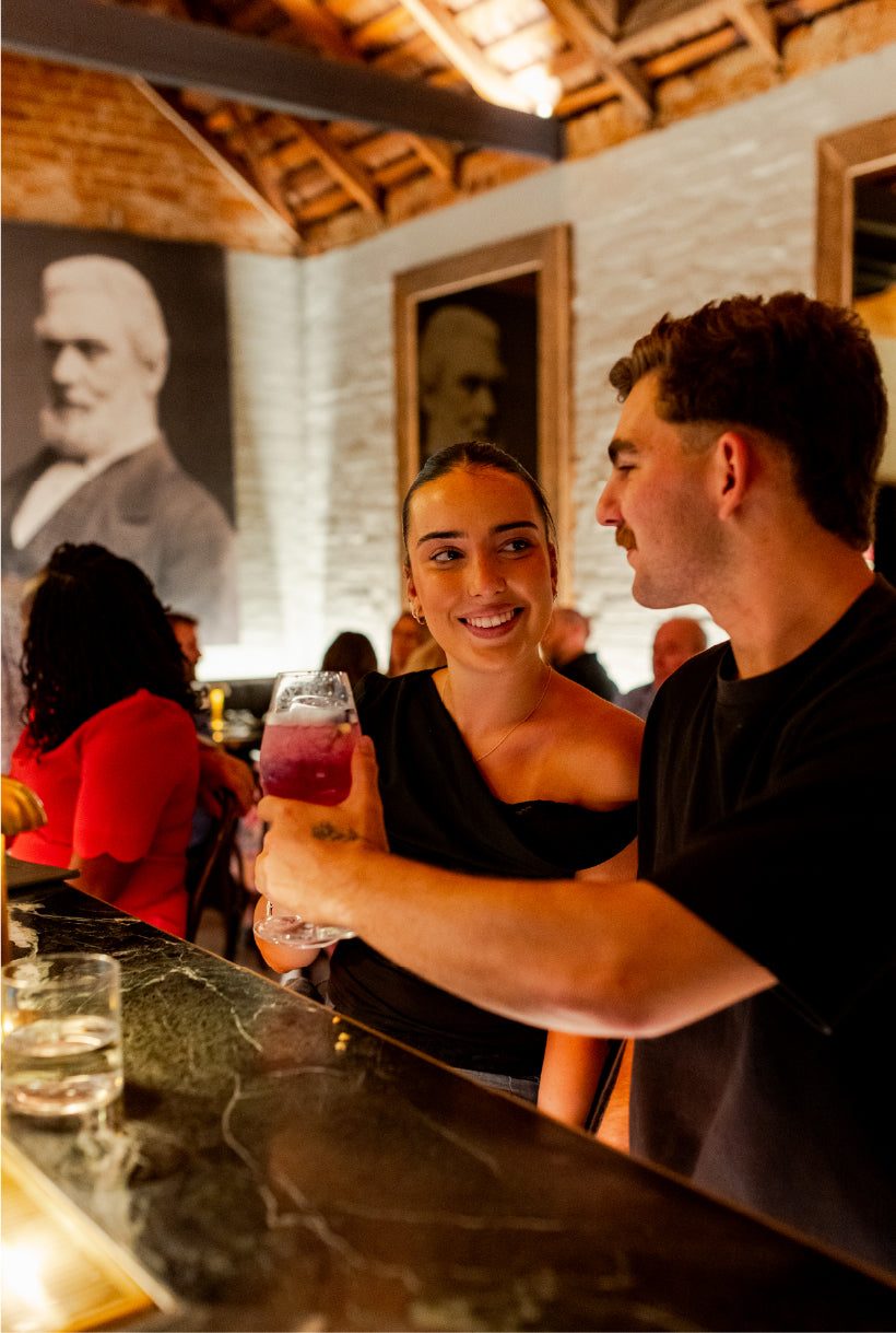 Guests sharing drinks at The Last Supper Club bar by candlelight